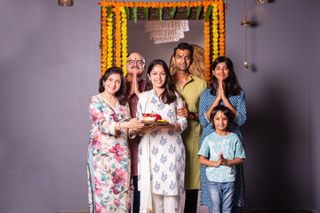 Indian happy family with puja thali in welcoming pose at entrance door