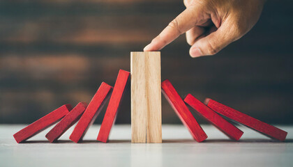 red wooden block halts cascading domino effect, concept of disruption and uniqueness