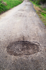 Poor condition of the road surface. Spring season. Hole in the asphalt, risk of movement by car,...