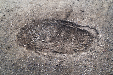 Poor condition of the road surface. Spring season. Hole in the asphalt, risk of movement by car,...