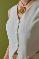 Close-up view of an elegant woman's upper body dressed in a chic white dress with a distinctive...