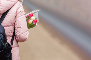 Person carrying a bouquet of tulips in the crook of their arm