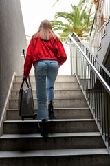 Young girl with a suitcase going up the stairs
