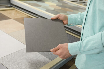 Man holding tile sample in store, closeup