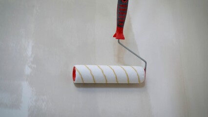 Painting with a roller brush. The roller paints the wall with gray paint. The master applies the...