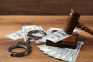 Judge's gavel, money and handcuffs on wooden table