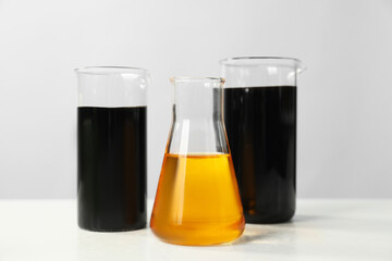 Beakers and flask with different types of oil on white table