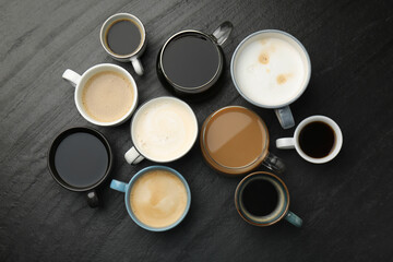 Different coffee drinks in cups on dark textured table, flat lay