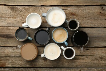 Different coffee drinks in cups on wooden table, flat lay