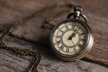 Pocket clock with chain on wooden table, closeup
