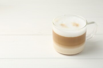 Aromatic coffee in glass cup on white wooden table, space for text