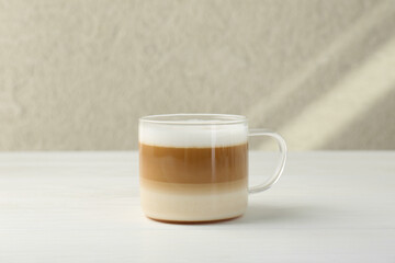 Aromatic coffee in glass cup on white wooden table