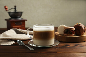 Aromatic coffee in cup, spoon and macarons on wooden table