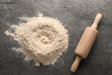Pile of flour and rolling pin on grey textured table, top view