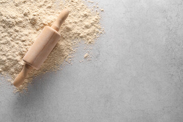 Pile of flour and rolling pin on light textured table, top view. Space for text