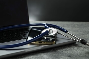 Modern electronic devices and stethoscope on grey table, closeup