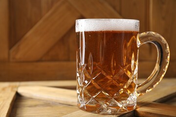 Mug with fresh beer on wooden crate, closeup. Space for text
