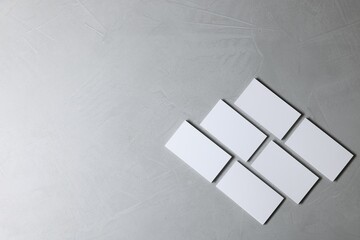 Blank business cards on light grey textured background, top view. Mockup for design