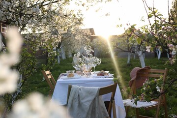 Stylish table setting with beautiful spring flowers in garden