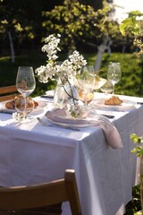 Beautiful table setting with spring flowers in garden on sunny day