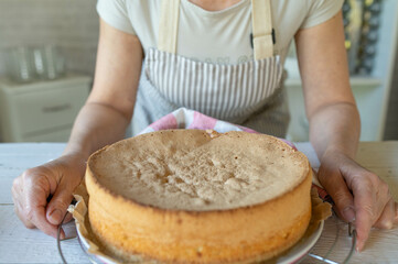 Woman with a fresh baked sponge cake base in the kitchen