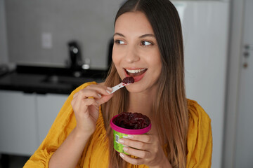 Brazilian girl eating acai sorbet ice cream frozen dessert looking to the side at home
