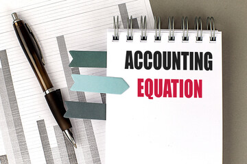 ACCOUNTING EQUATION text on notebook with chart on gray background