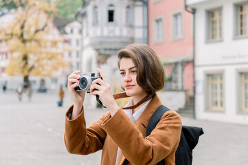 Young woman using a camera taking photos visiting a city