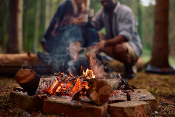 Close up of campfire with  couple in background.