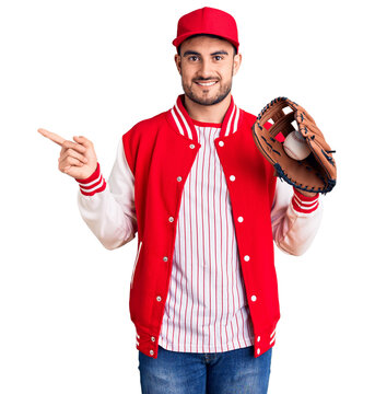 Young handsome man holding baseball gloves smiling happy pointing with hand and finger to the side