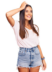 Obraz premium Young hispanic woman wearing casual white tshirt smiling confident touching hair with hand up gesture, posing attractive and fashionable