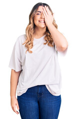 Fototapeta premium Young caucasian woman wearing casual clothes covering one eye with hand, confident smile on face and surprise emotion.