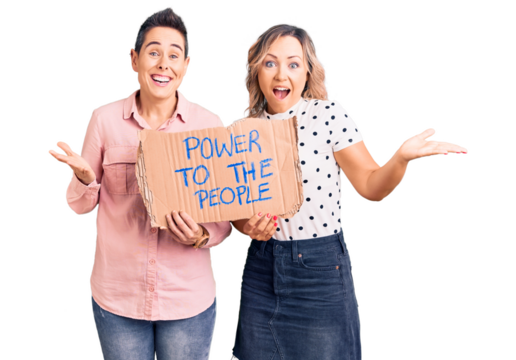 Couple of women holding power to the people banner celebrating victory with happy smile and winner expression with raised hands