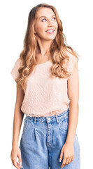 Obraz premium Young beautiful caucasian woman with blond hair wearing casual clothes smiling looking to the side and staring away thinking.