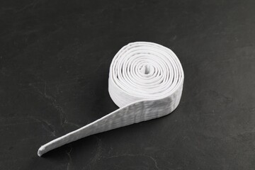 Rolled white karate belt on gray background