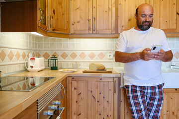 Bearded man using smartphone in kitchen