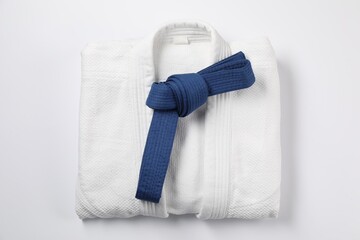 Blue karate belt and kimono on white background, top view