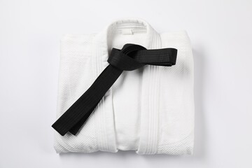 Black karate belt and kimono on white background, top view