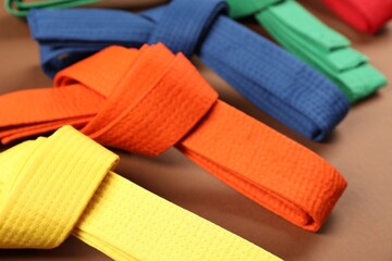 Colorful karate belts on brown background, closeup