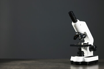 Modern microscope on grey table, space for text