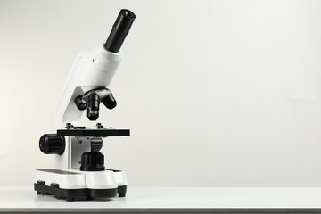Modern microscope on white table, space for text