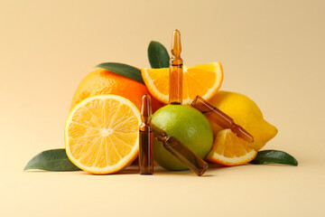 Skincare ampoules with vitamin C, different citrus fruits and leaves on beige background