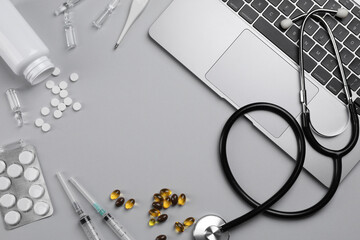 Flat lay composition with laptop and medical supplies on light grey background. Space for text