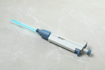 Laboratory analysis. Micropipette with liquid on light grey marble table