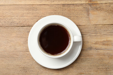 Cup of aromatic coffee on wooden table, top view