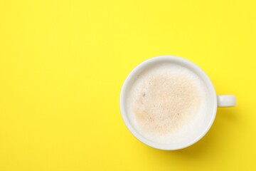 Aromatic coffee in cup on yellow background, top view. Space for text