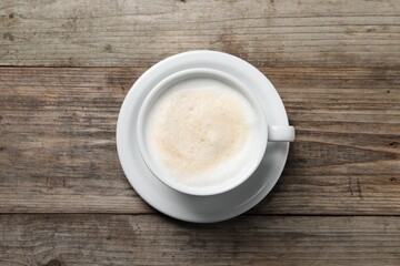 Aromatic coffee in cup on wooden table, top view