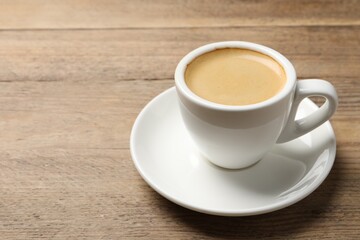 Aromatic coffee in cup on wooden table. Space for text