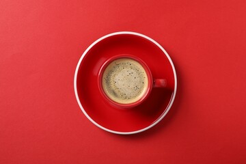 Tasty coffee in cup on red background, top view