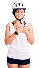 Beautiful young woman with short hair wearing bike helmet smiling with hands on chest with closed eyes and grateful gesture on face. health concept.